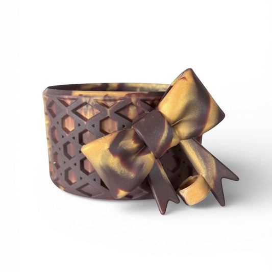 Next Nirvana chocolate gold waffle-textured silicone tumbler boot with a matching 3D bow straw topper.
