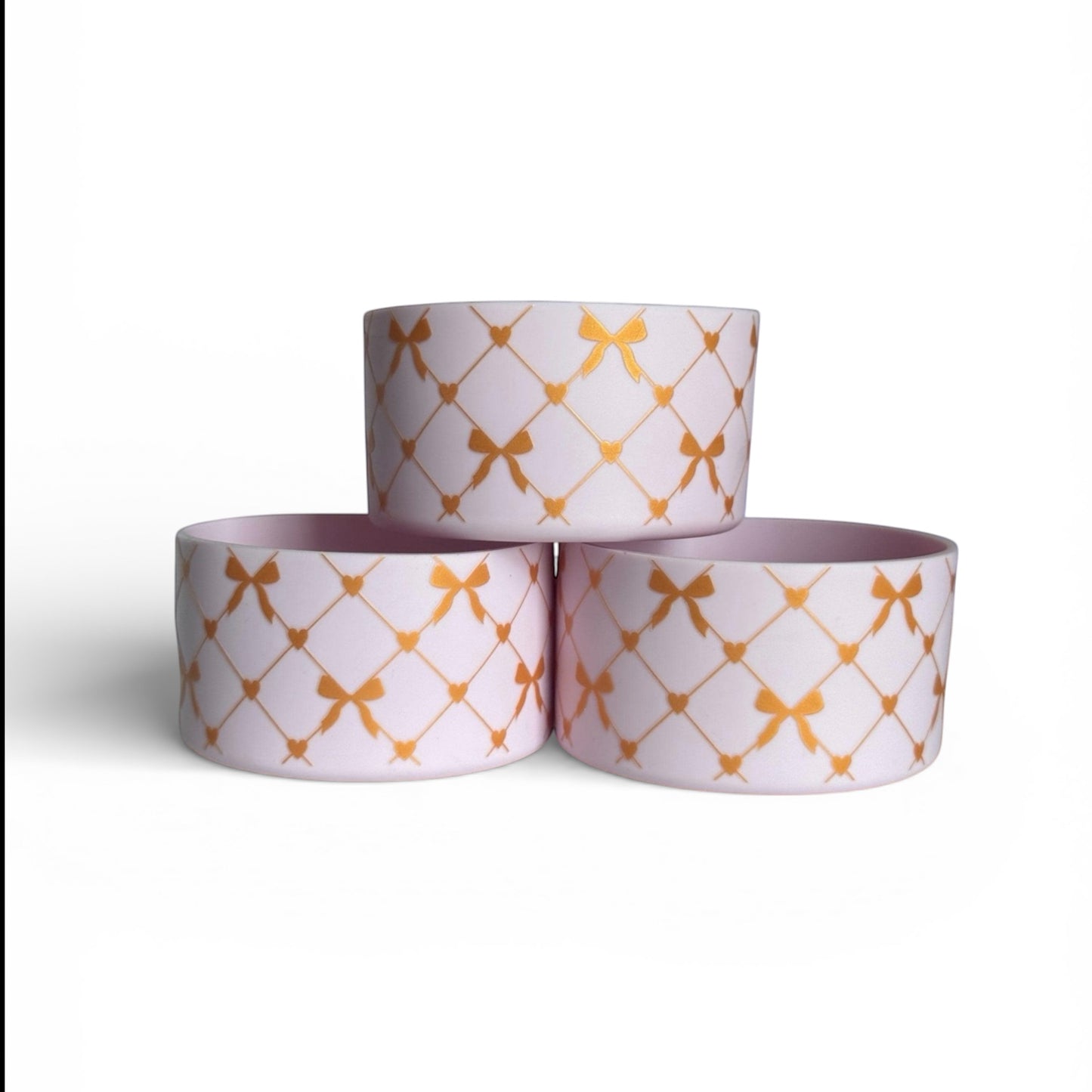 Next Nirvana silicone tumbler boot in light pink with a gold criss-cross bow and heart pattern for 20-40oz tumblers.