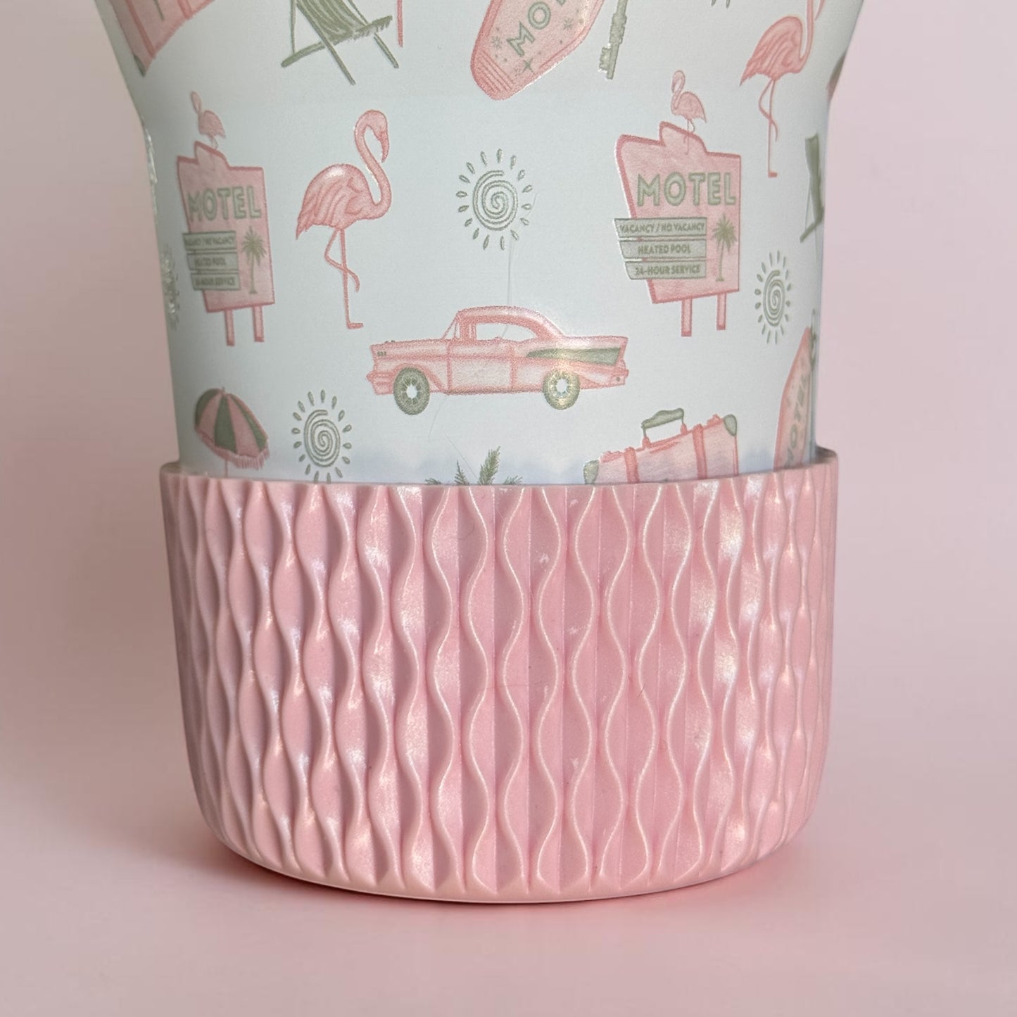 Next Nirvana rose pink shimmer silicone tumbler boot with 3D wave texture on a patterned travel cup