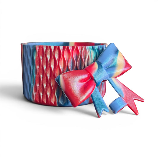 Next Nirvana silicone tumbler boot and 3D bow straw topper in a red, blue, and yellow shimmer wave pattern.