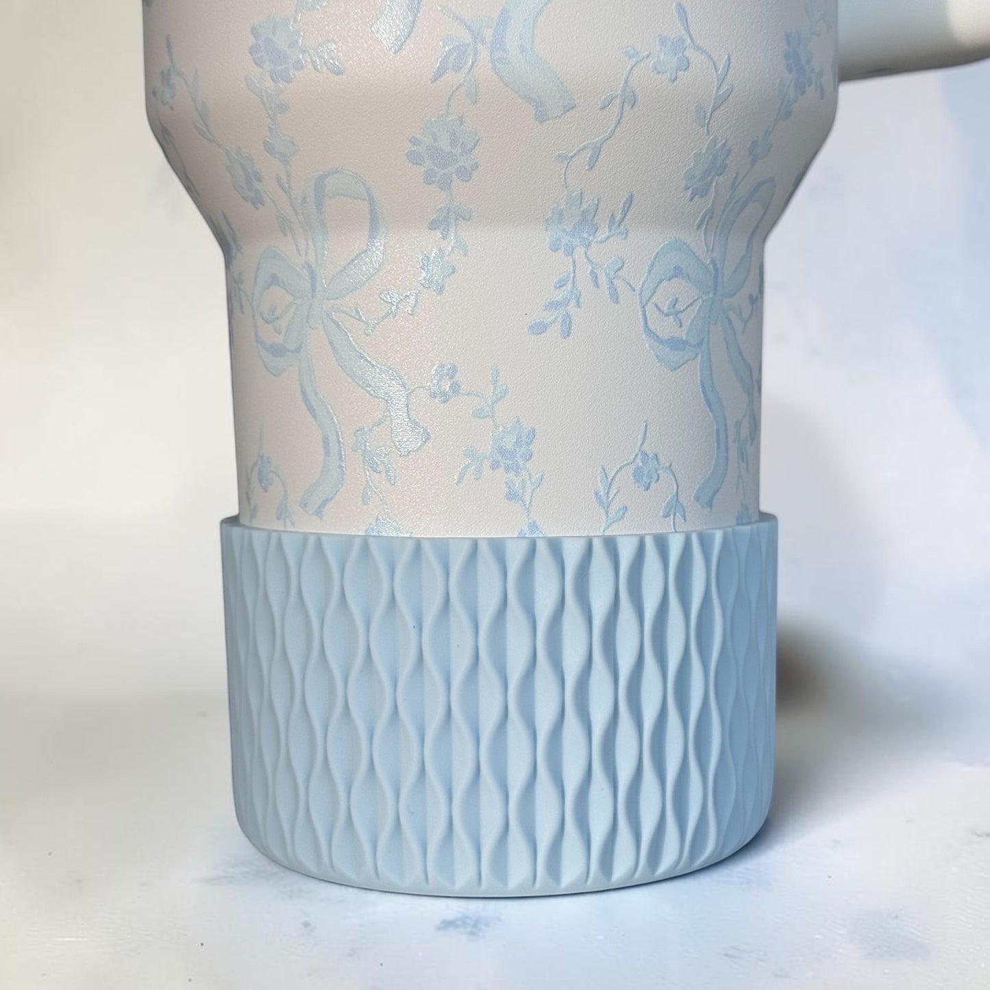 Next Nirvana matte light blue silicone tumbler boot with a 3D wave texture on a floral patterned tumbler base.