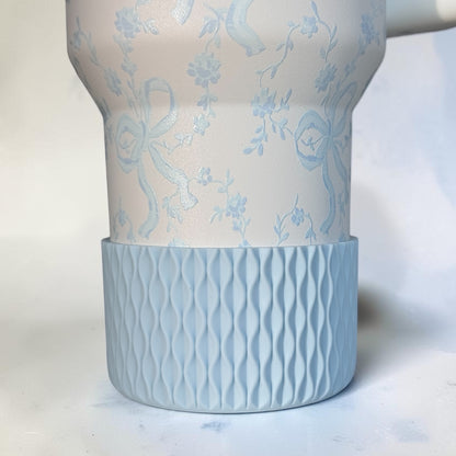 Next Nirvana matte light blue silicone tumbler boot with a 3D wave texture on a floral patterned tumbler base.
