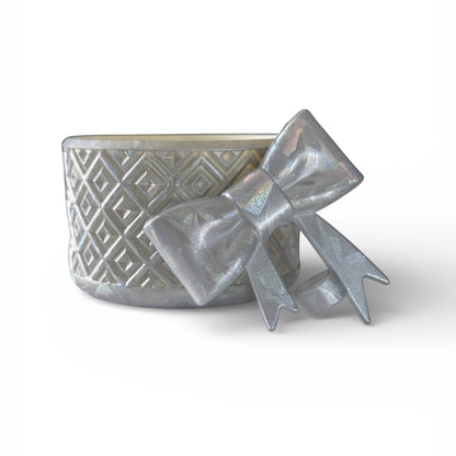 Next Nirvana silver diamond-pattern silicone tumbler boot with a matching 3D bow straw topper on a white background.
