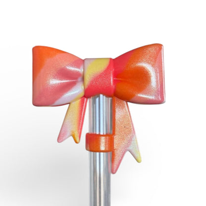 Next Nirvana Summer Heat Shimmer 3D silicone bow straw topper in a vibrant orange, pink, and yellow swirl pattern.