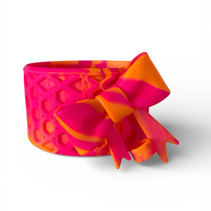 Next Nirvana Summer Sunset waffle-textured silicone tumbler boot and matching 3D bow straw topper in pink and orange.