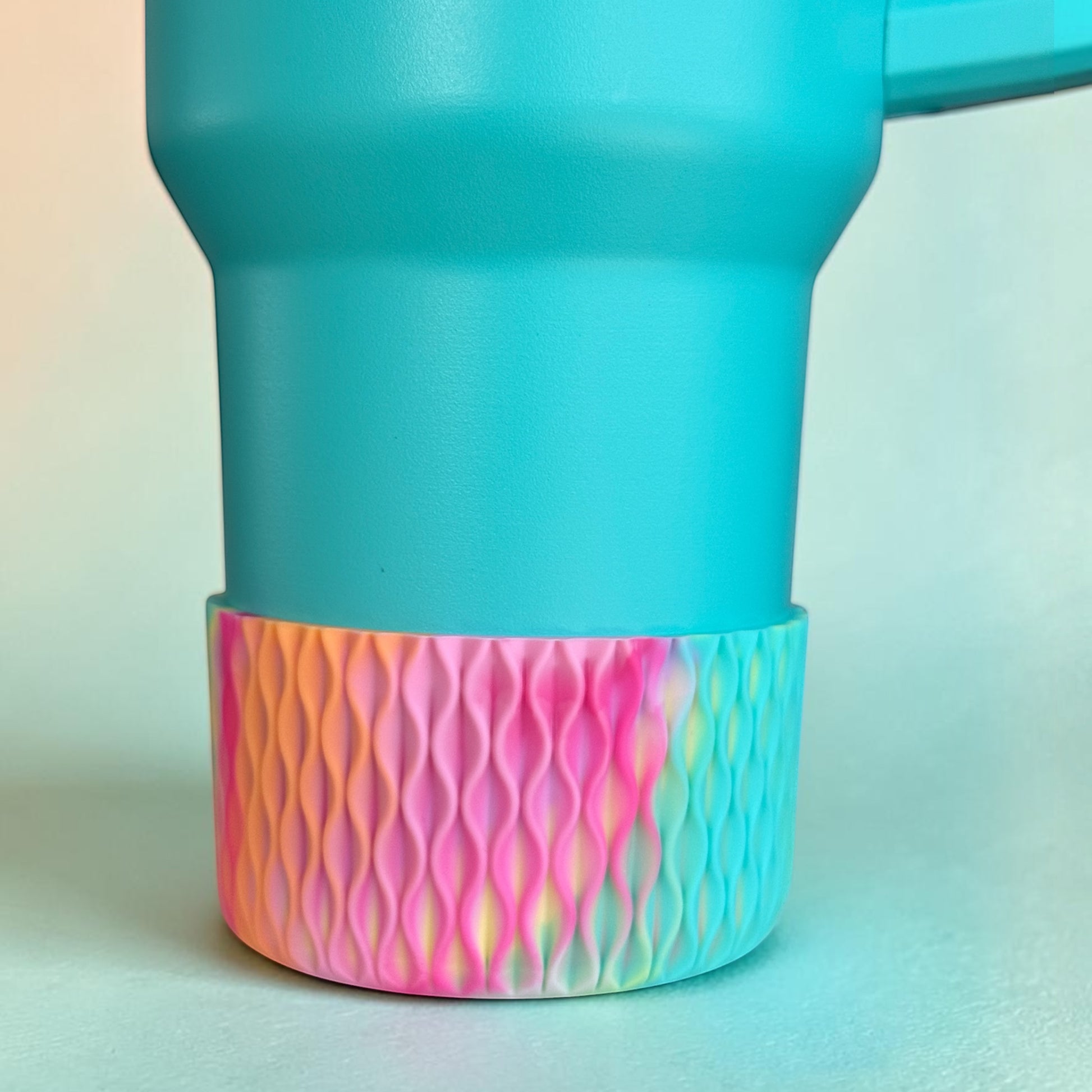 Next Nirvana silicone tumbler boot with a 3D wave texture in a vibrant pink, orange, and yellow tie-dye pattern.